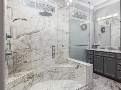 Modern bathroom shower featuring glass enclosure, marble tiles, built-in bench, and sleek showerhead, enhancing comfort and style for bathroom remodels.