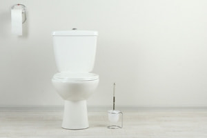 A clean white toilet stands against a light wall