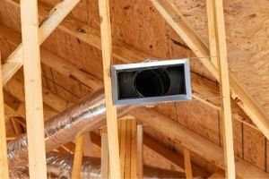 Air duct in a residential attic, showcasing aging ductwork and wooden framing, illustrating the importance of air duct replacement for HVAC efficiency and home health.