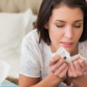 Woman holding tissue, showing signs of allergy discomfort, relevant to spring allergy concerns and indoor air quality.