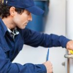 A worker in blue uniform using a wrench on plumbing tools, representing PAC Plumbing, Heating, Air Conditioning services.