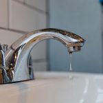 Chrome faucet with dripping water, highlighting modern design for PAC Plumbing, Heating, Air Conditioning services.