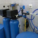 Water filtration system with blue tanks, pipes, and gauges for PAC Plumbing services improving water quality.