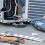 Technician repairing an air conditioning unit with tools at PAC Plumbing, Heating, and Air Conditioning in Staten Island.