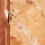 Leaking copper pipe with water flowing, illustrating the importance of prompt leak detection and repair services by PAC Plumbing, Heating, and Air Conditioning.
