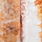 Ice forming around a copper pipe with water dripping, illustrating the risk of frozen pipes during winter, relevant to plumbing maintenance tips.